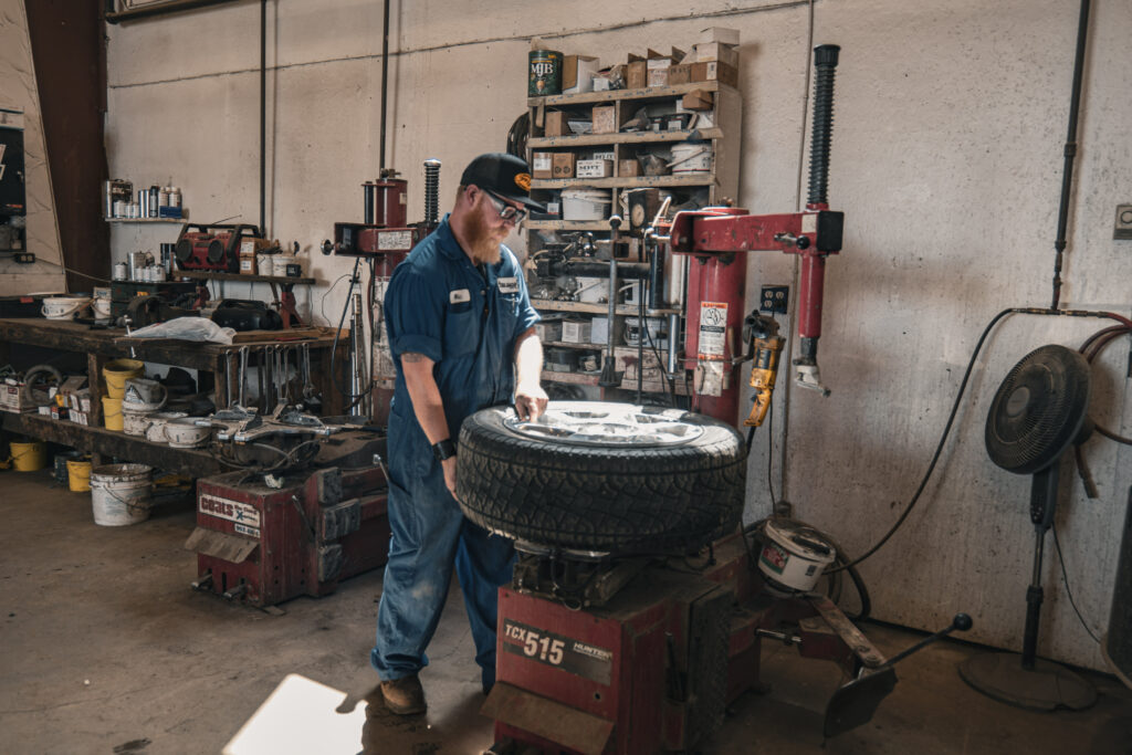 A staff member focused on fixing a damaged tire using professional tools.