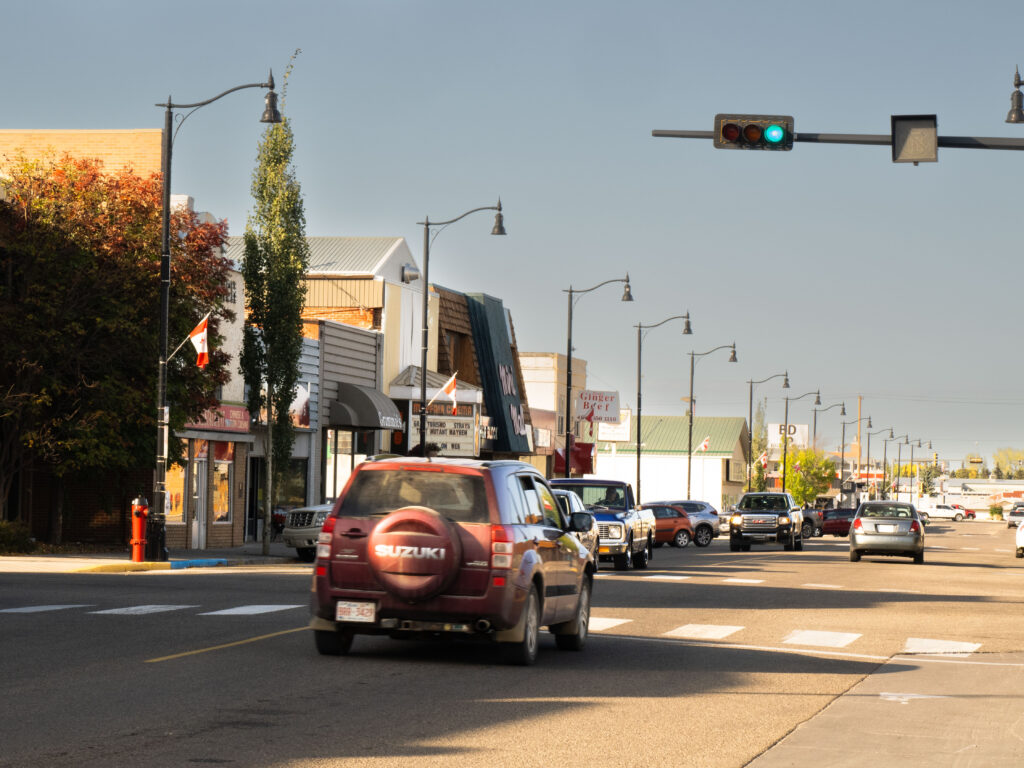 Cars lining the bustling main street of Olds, showcasing vibrant local businesses and the town's active commercial heart.